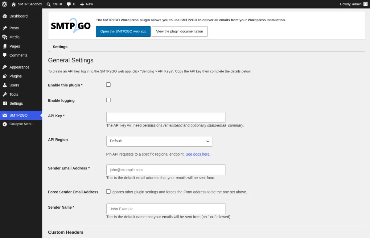 SMTP2GO 1.17.0 General Settings page inside a real WordPress install showing the SMTP2GO logo, the description The SMTP2GO Wordpress plugin allows you to use SMTP2GO to deliver all emails from your Wordpress installation, the Open the SMTP2GO web app and View the plugin documentation buttons, the Settings tab, the Enable this plugin and Enable logging checkboxes, the API Key text field with the helper line about /email/send and /stats/email_summary permissions, the API Region drop-down set to Default, the Sender Email Address field with john@example.com placeholder, the Force Sender Email Address toggle, the Sender Name field with John Example placeholder, and the Custom Headers section heading.